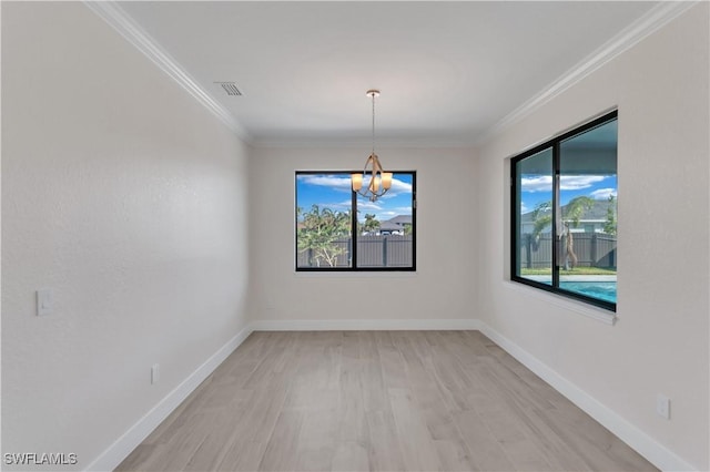 empty room with a chandelier, light hardwood / wood-style flooring, and crown molding