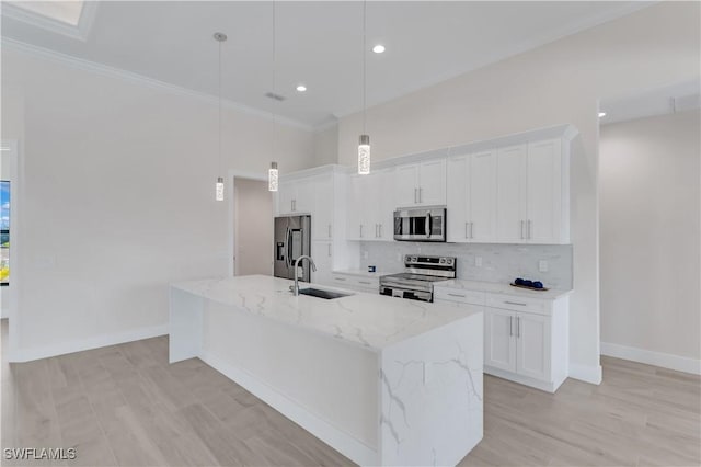 kitchen featuring pendant lighting, white cabinets, stainless steel appliances, and a kitchen island with sink