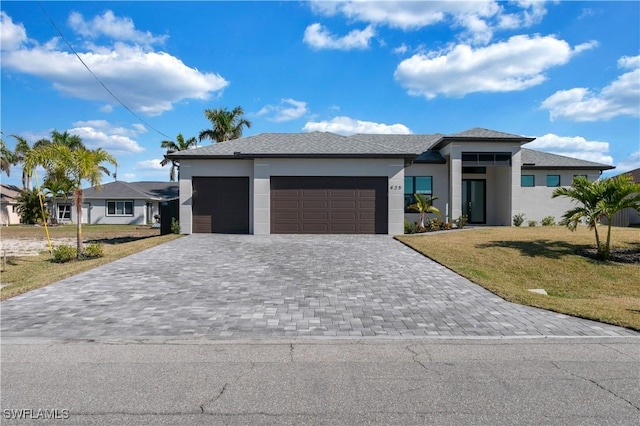 prairie-style home featuring a garage and a front lawn