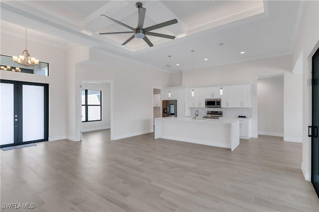 kitchen with a kitchen island with sink, white cabinets, ceiling fan with notable chandelier, hanging light fixtures, and stainless steel appliances