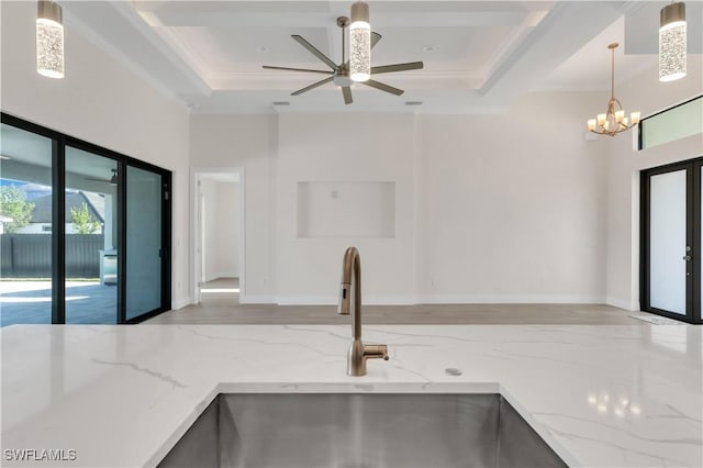 kitchen with ceiling fan with notable chandelier, sink, light stone countertops, ornamental molding, and decorative light fixtures