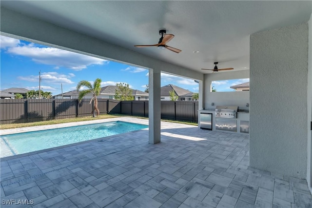 view of swimming pool with area for grilling, ceiling fan, a patio area, and exterior kitchen