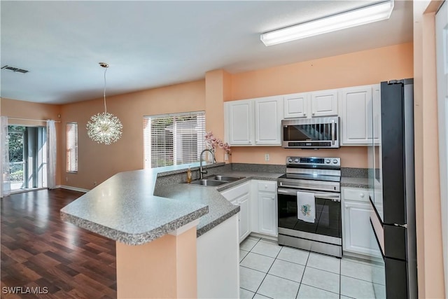 kitchen featuring appliances with stainless steel finishes, hanging light fixtures, kitchen peninsula, sink, and white cabinetry