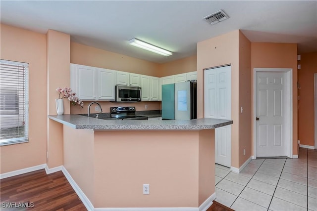 kitchen with stainless steel appliances, white cabinetry, sink, and kitchen peninsula