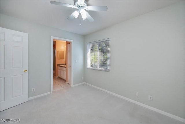 unfurnished bedroom with ensuite bath, light colored carpet, and ceiling fan