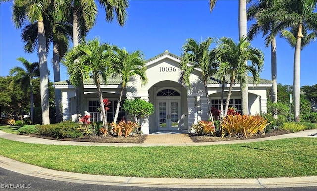 mediterranean / spanish house featuring french doors and a front lawn