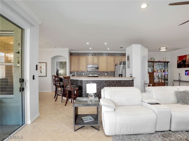 living room with light tile patterned floors, recessed lighting, arched walkways, and ornamental molding