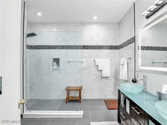 bathroom featuring double vanity, a walk in shower, and a sink