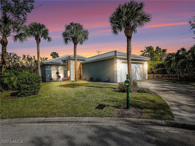 mid-century inspired home with a tiled roof, concrete driveway, a front yard, stucco siding, and an attached garage