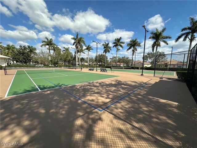 view of tennis court with community basketball court and fence