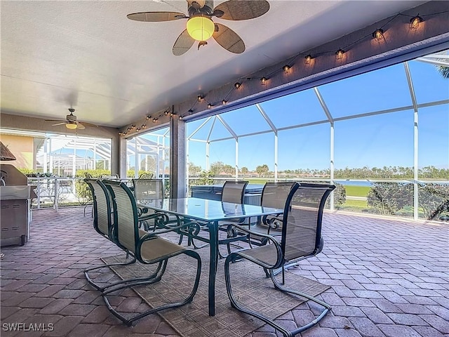 view of patio featuring a bar, a lanai, ceiling fan, and a water view