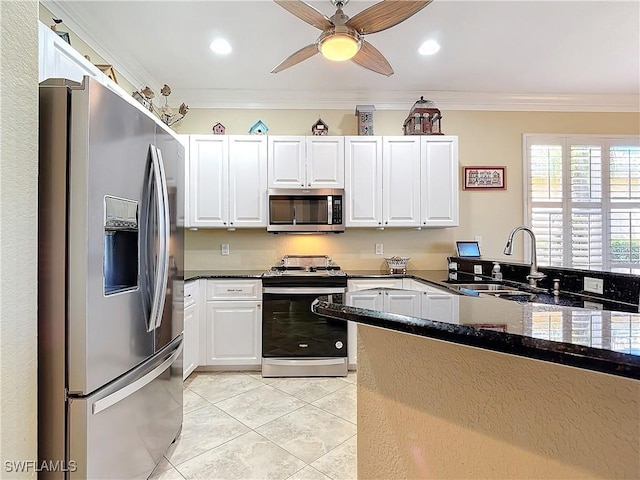 kitchen featuring stainless steel appliances, light tile patterned floors, crown molding, white cabinetry, and dark stone counters