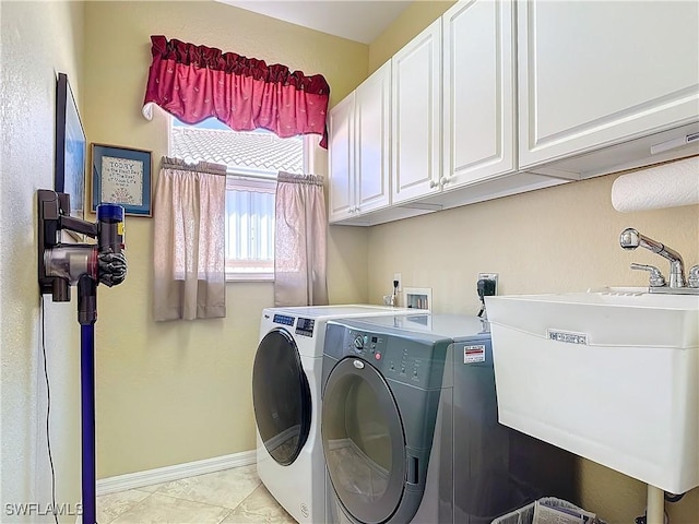 laundry area featuring sink, washer and clothes dryer, light tile patterned floors, and cabinets