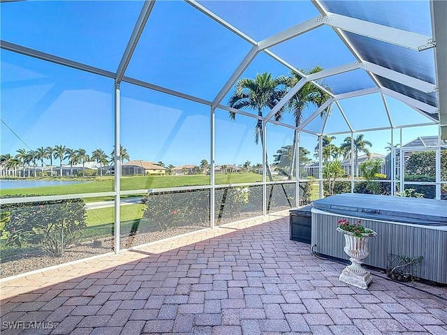 view of patio featuring a lanai, a hot tub, and a water view