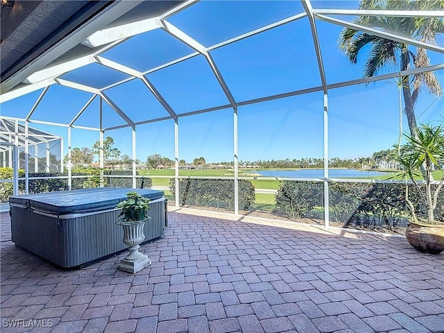 view of patio with glass enclosure and a hot tub