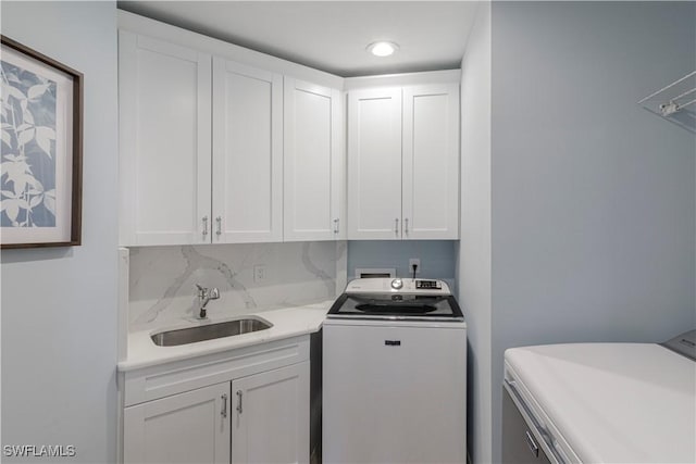 laundry room featuring cabinets, separate washer and dryer, and sink