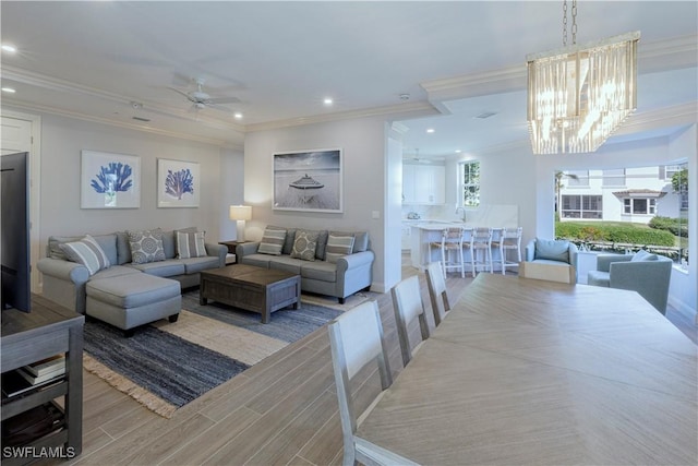 living room featuring ceiling fan with notable chandelier and ornamental molding