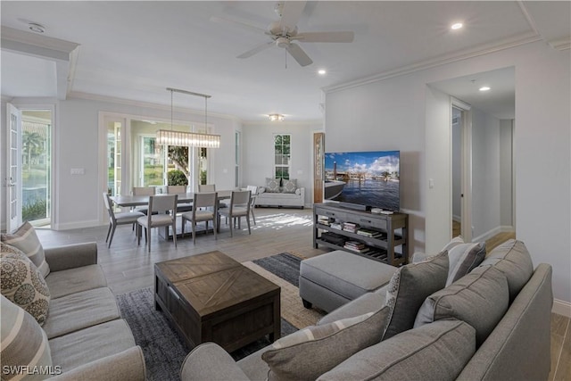 living room featuring hardwood / wood-style floors, ceiling fan with notable chandelier, and ornamental molding