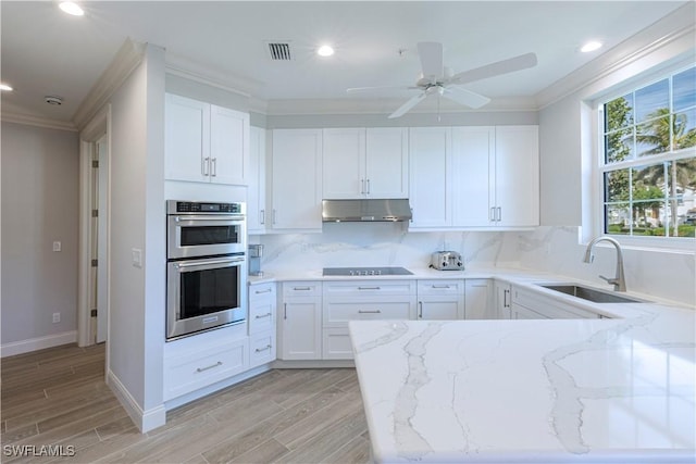 kitchen featuring light stone countertops, sink, double oven, backsplash, and white cabinets