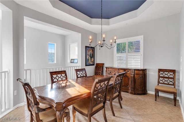 dining area featuring a tray ceiling, a wealth of natural light, light tile patterned flooring, and a notable chandelier