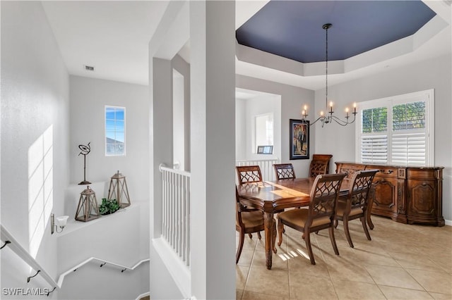 tiled dining room featuring an inviting chandelier and a tray ceiling