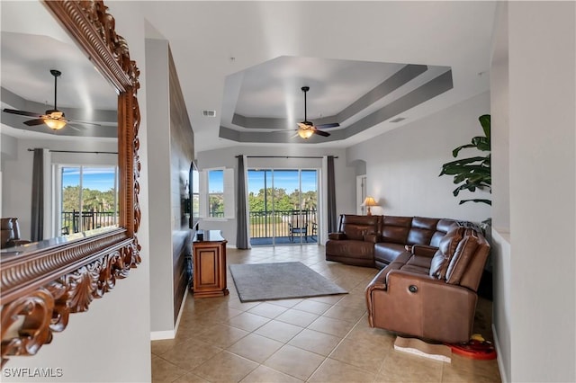 tiled living room featuring ceiling fan and a tray ceiling