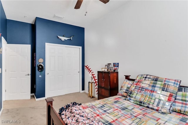 bedroom with ceiling fan, light colored carpet, and a closet