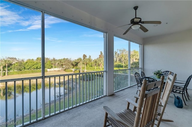 sunroom / solarium with ceiling fan and a water view