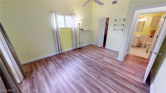 unfurnished bedroom featuring ensuite bath, light hardwood / wood-style flooring, a closet, and ceiling fan