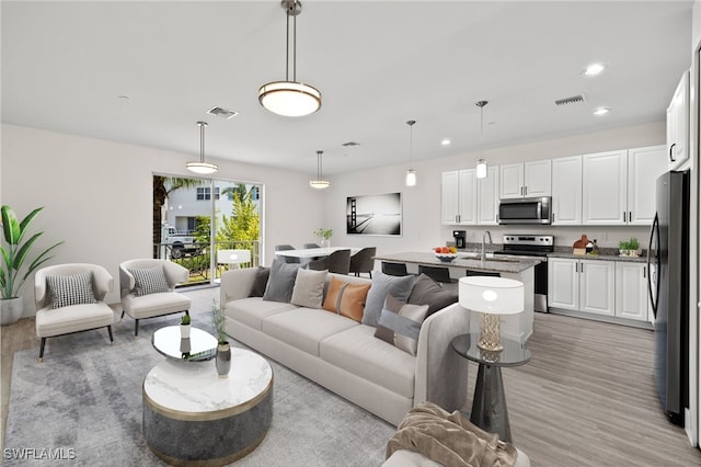 living area with recessed lighting, visible vents, and light wood-style floors