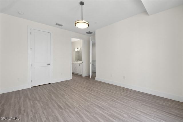 unfurnished room with light wood finished floors, baseboards, and visible vents