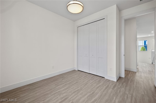 unfurnished bedroom with a closet, wood finished floors, and baseboards