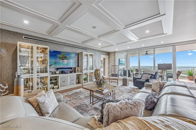 living room with a wealth of natural light, ceiling fan, and coffered ceiling