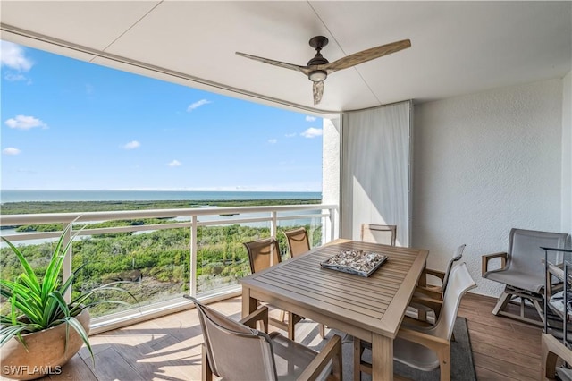 balcony with ceiling fan, a water view, and a view of the beach