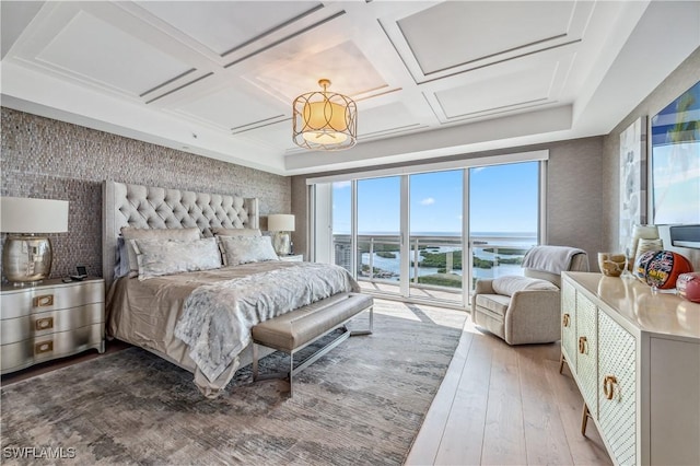 bedroom with access to exterior, a water view, coffered ceiling, and hardwood / wood-style flooring