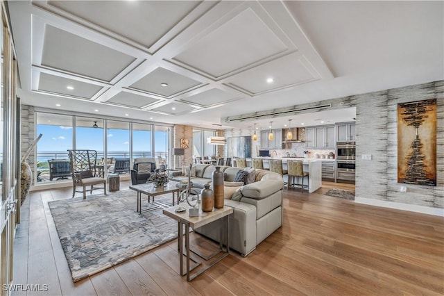 living room featuring light hardwood / wood-style flooring, a wall of windows, and coffered ceiling