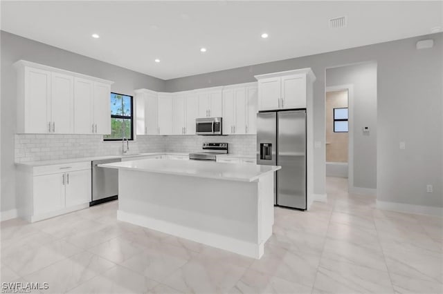 kitchen featuring sink, a center island, decorative backsplash, white cabinets, and appliances with stainless steel finishes