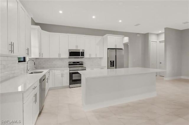 kitchen featuring a center island, white cabinets, sink, tasteful backsplash, and stainless steel appliances