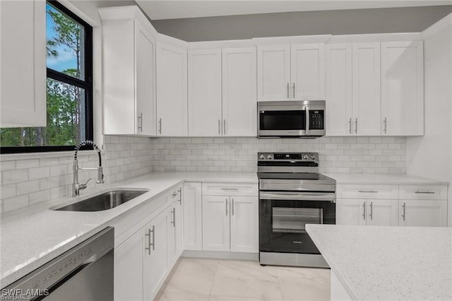 kitchen featuring decorative backsplash, light stone counters, stainless steel appliances, sink, and white cabinets