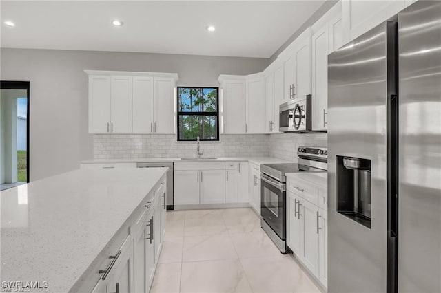 kitchen featuring decorative backsplash, appliances with stainless steel finishes, light stone counters, sink, and white cabinetry