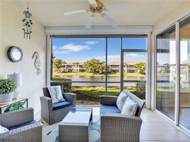 sunroom featuring ceiling fan and a water view