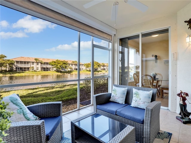 sunroom with ceiling fan and a water view