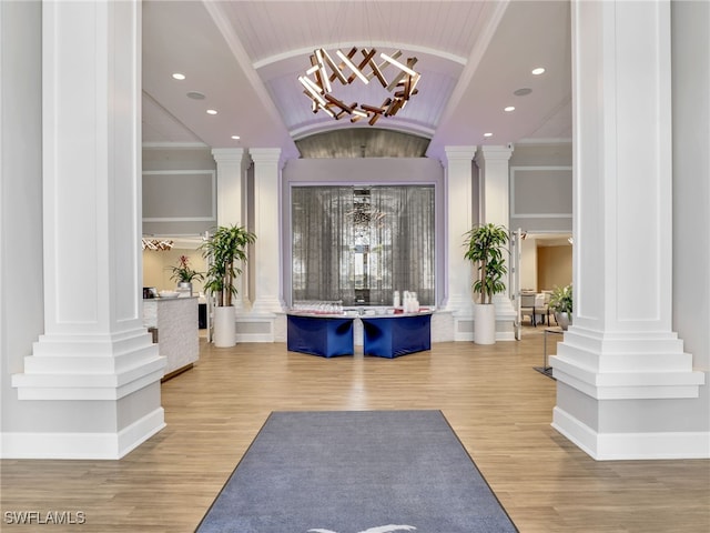 interior space featuring hardwood / wood-style floors, an inviting chandelier, and ornate columns