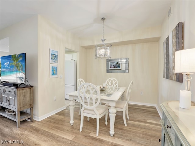 dining room featuring light wood-type flooring and a notable chandelier