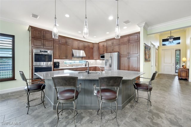 kitchen featuring a kitchen breakfast bar, hanging light fixtures, appliances with stainless steel finishes, and tasteful backsplash