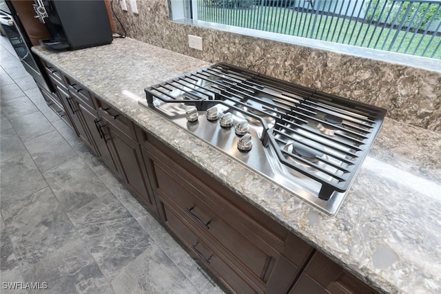 details featuring light stone countertops, dark brown cabinetry, and stainless steel gas cooktop