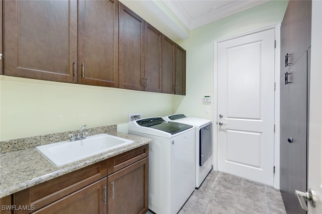 clothes washing area with cabinets, sink, separate washer and dryer, and crown molding