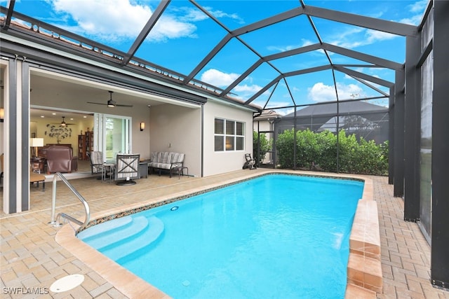 view of pool with glass enclosure, outdoor lounge area, ceiling fan, and a patio area