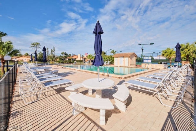 view of swimming pool featuring a patio area and a shed