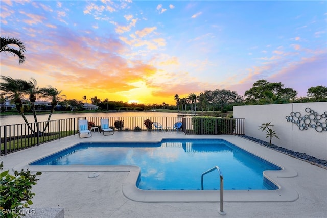 pool at dusk featuring a water view